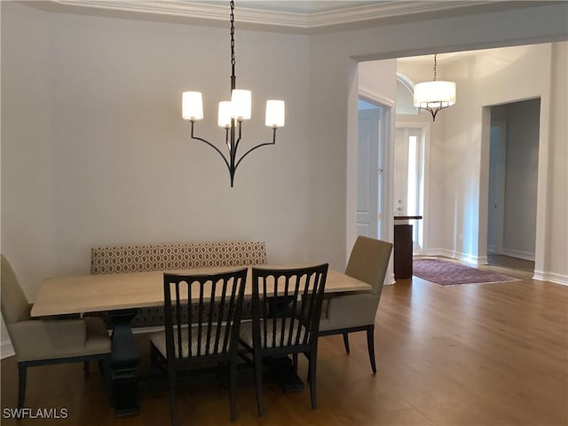 dining room with dark hardwood / wood-style floors, ornamental molding, and a notable chandelier