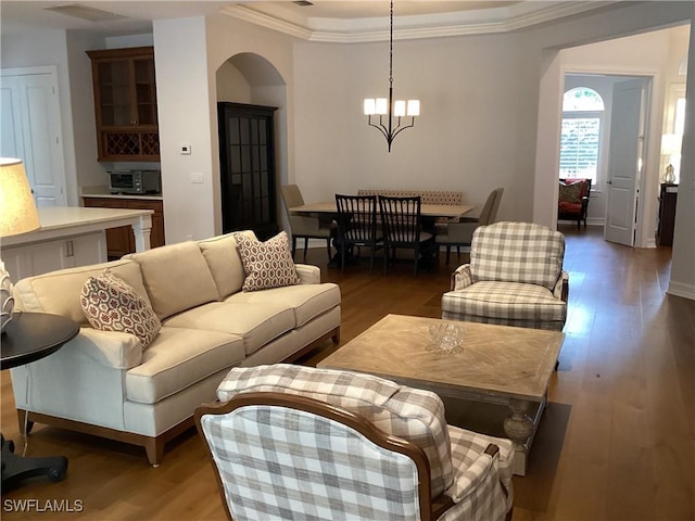 living room with a chandelier, crown molding, dark hardwood / wood-style floors, and a tray ceiling