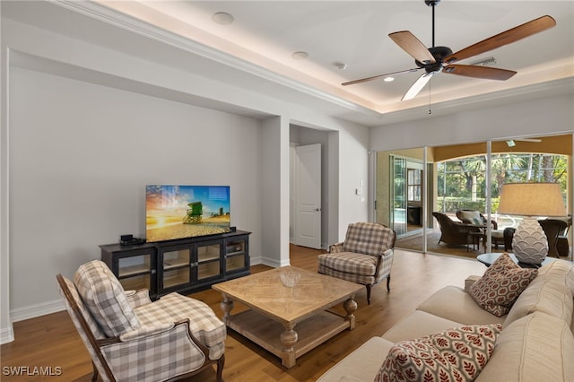 living room featuring a tray ceiling, light hardwood / wood-style flooring, and ceiling fan