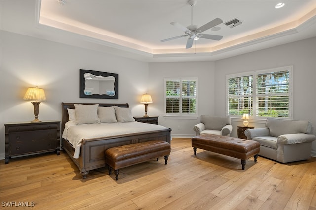 bedroom featuring ceiling fan, a tray ceiling, and light hardwood / wood-style flooring