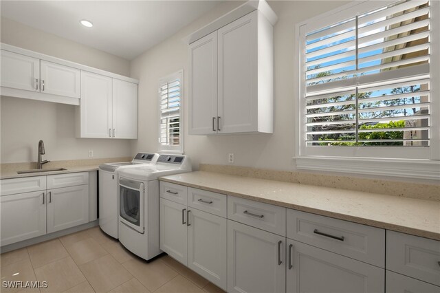 washroom featuring separate washer and dryer, sink, cabinets, and light tile patterned flooring