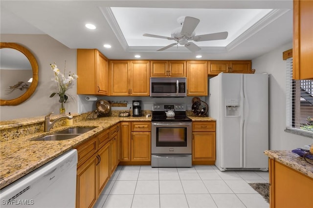 kitchen with sink, a raised ceiling, light stone countertops, and appliances with stainless steel finishes