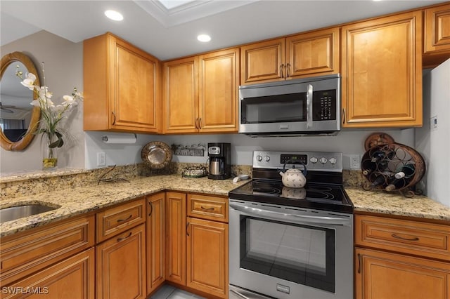 kitchen with sink, stainless steel appliances, and light stone countertops