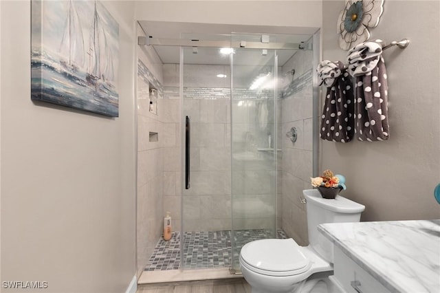 bathroom with toilet, a shower with shower door, and vanity