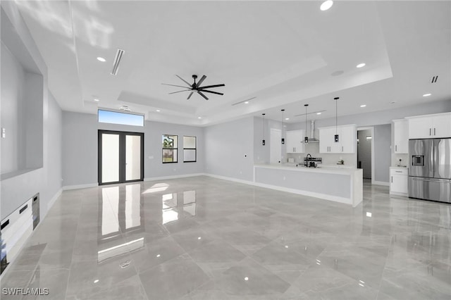 unfurnished living room featuring ceiling fan, a tray ceiling, and french doors