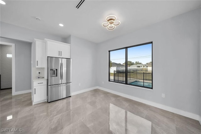 kitchen with stainless steel refrigerator with ice dispenser and white cabinetry