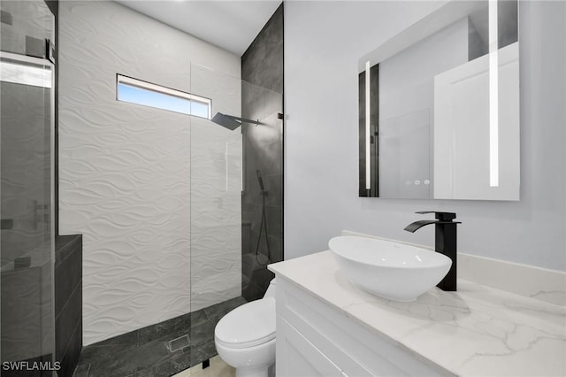 bathroom with toilet, vanity, and a tile shower