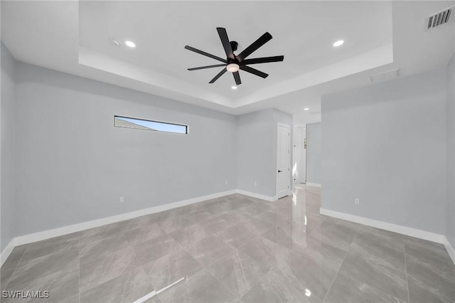 unfurnished room with ceiling fan and a raised ceiling