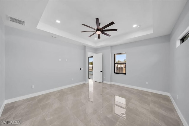 unfurnished room with ceiling fan and a tray ceiling