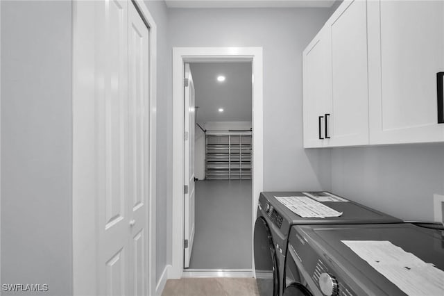 clothes washing area with cabinets and washer and clothes dryer