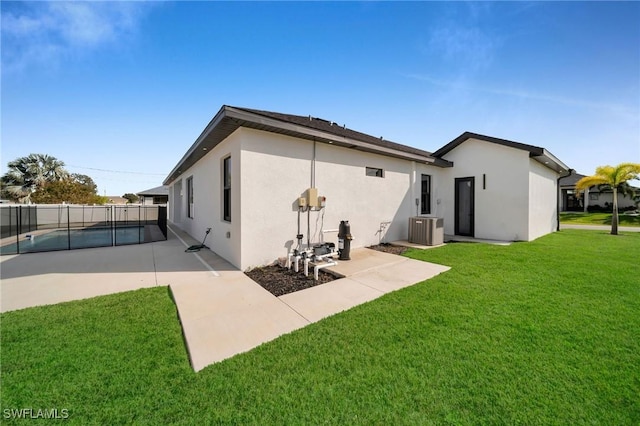 rear view of house featuring a lawn, central AC unit, a patio, and a fenced in pool