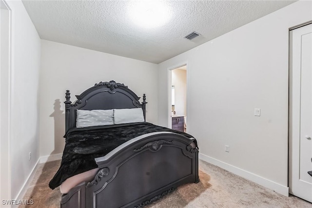 bedroom with light colored carpet and a textured ceiling