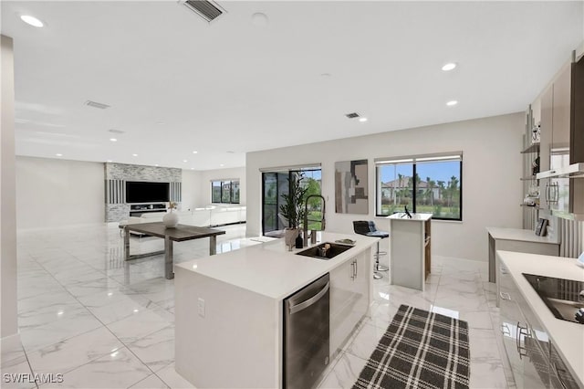 kitchen featuring a kitchen island with sink, sink, stainless steel dishwasher, and black electric stovetop