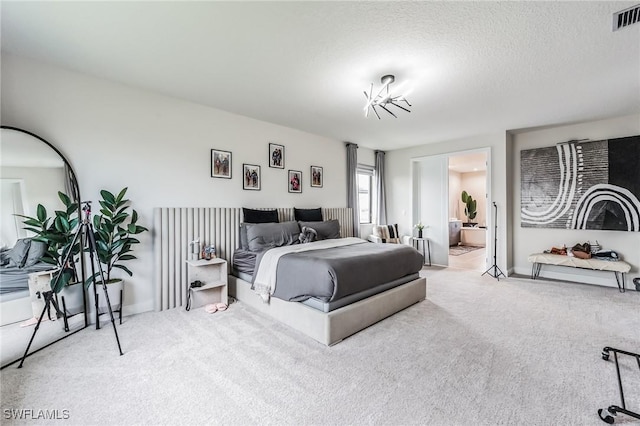 carpeted bedroom with a textured ceiling and ensuite bath