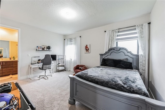 bedroom with carpet floors, a textured ceiling, and ensuite bath