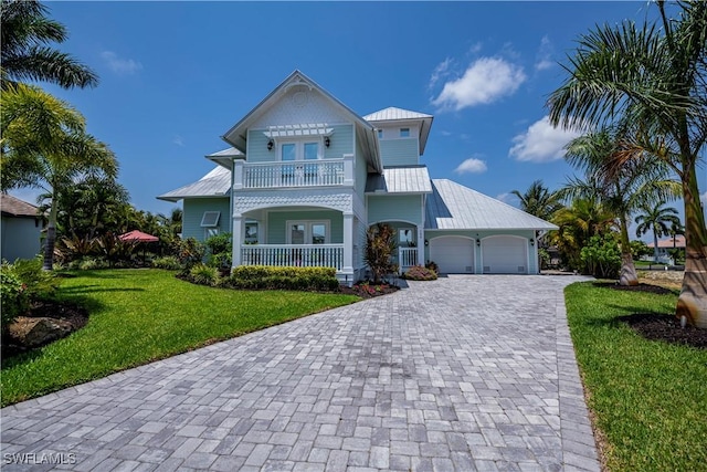 view of front of home with a garage, a balcony, and a front yard