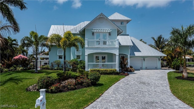 view of front of house with a garage, a front yard, french doors, and a balcony