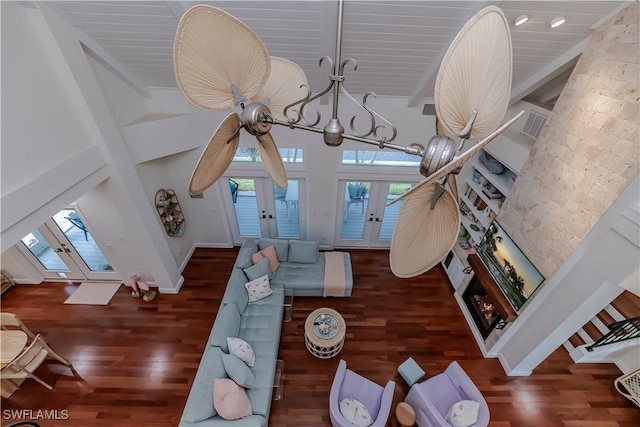 living room with french doors, a towering ceiling, dark hardwood / wood-style floors, and beamed ceiling