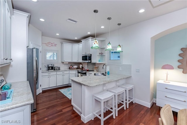 kitchen featuring hanging light fixtures, kitchen peninsula, white cabinets, and appliances with stainless steel finishes