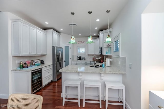 kitchen featuring wine cooler, white cabinetry, hanging light fixtures, stainless steel appliances, and light stone countertops