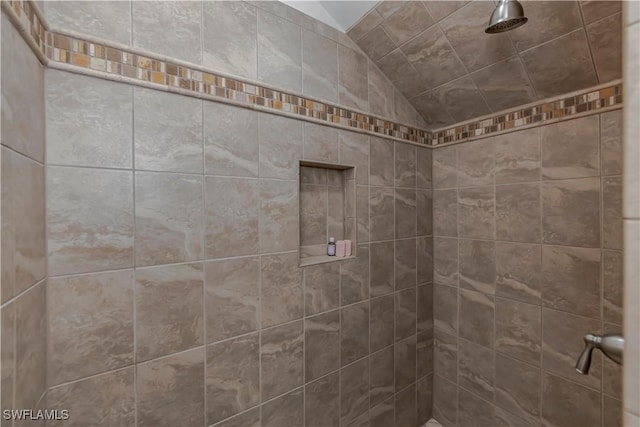 bathroom with vaulted ceiling and tiled shower