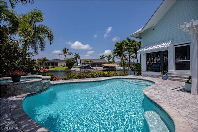 view of swimming pool with an in ground hot tub, a water view, and a patio