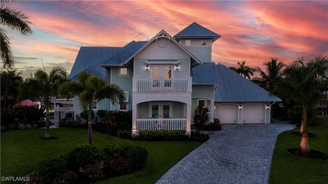 view of front of property with a garage, a balcony, covered porch, and a lawn