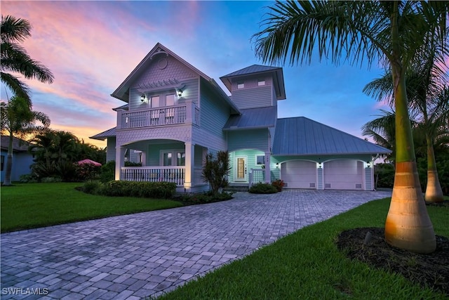 view of front of property with a balcony, a garage, and a lawn