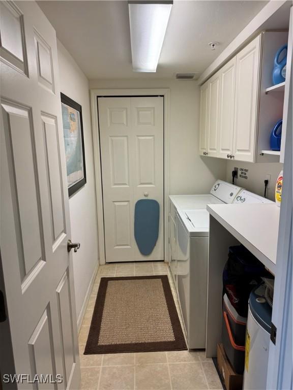 laundry room with cabinets, light tile patterned floors, and independent washer and dryer