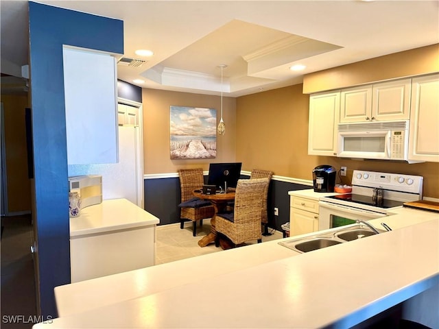 kitchen featuring a raised ceiling, white appliances, pendant lighting, crown molding, and sink