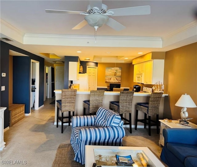 carpeted living room with ceiling fan, a tray ceiling, and ornamental molding