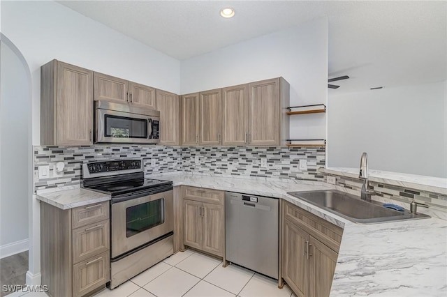 kitchen featuring light tile patterned floors, ceiling fan, stainless steel appliances, decorative backsplash, and sink