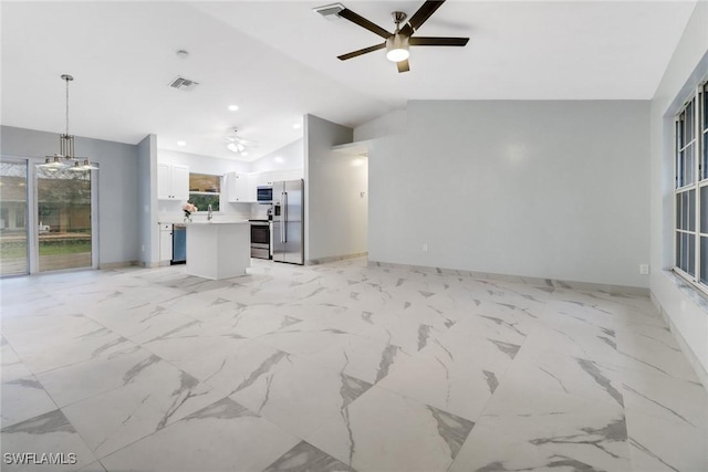 unfurnished living room featuring ceiling fan with notable chandelier and vaulted ceiling