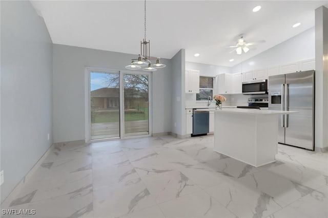 kitchen with white cabinetry, vaulted ceiling, a kitchen island, pendant lighting, and stainless steel appliances