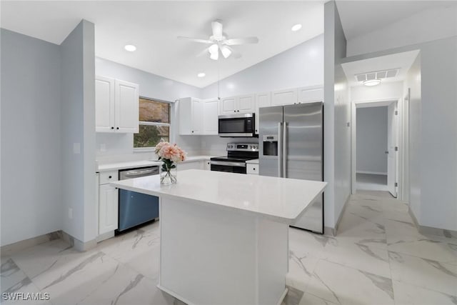 kitchen with lofted ceiling, white cabinetry, a center island, appliances with stainless steel finishes, and ceiling fan