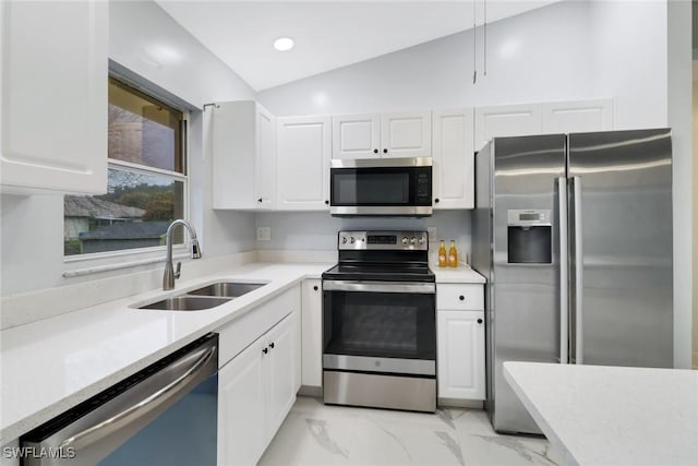 kitchen with stainless steel appliances, white cabinetry, vaulted ceiling, and sink