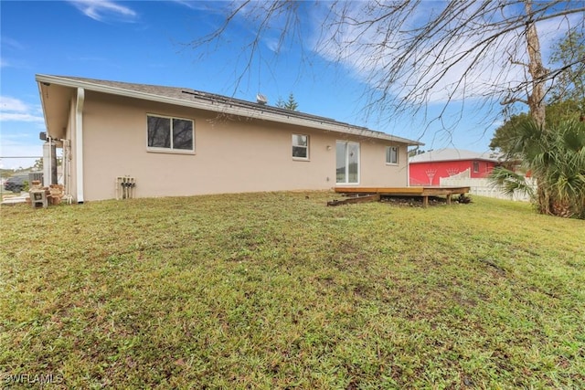 rear view of property featuring a wooden deck and a lawn