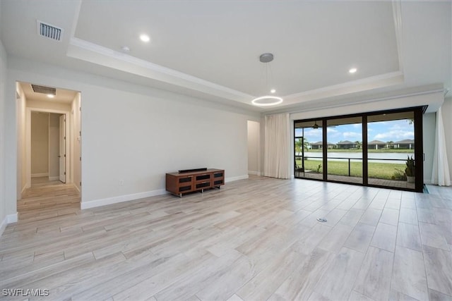 spare room featuring crown molding, a raised ceiling, visible vents, light wood-style flooring, and baseboards