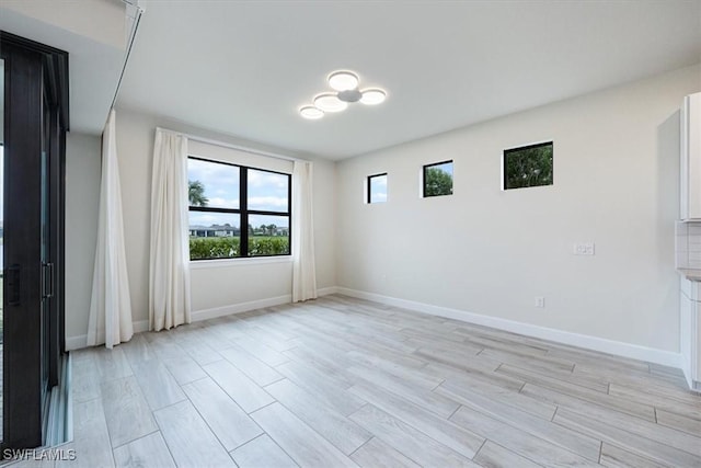 unfurnished room with light wood-type flooring and baseboards