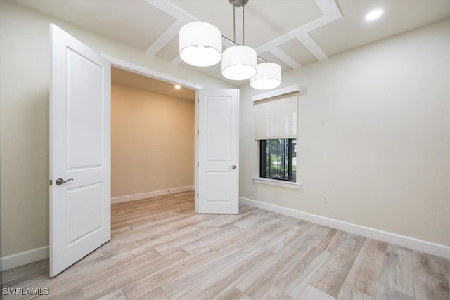 spare room featuring light wood-style floors, beam ceiling, and baseboards