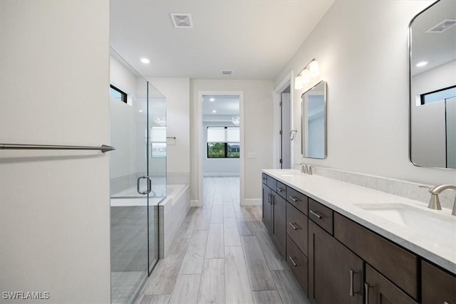 full bath featuring double vanity, a shower stall, visible vents, and a sink