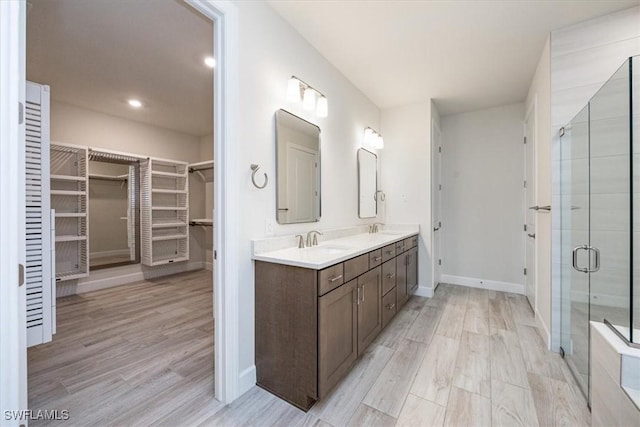 bathroom featuring a stall shower, a walk in closet, a sink, and double vanity