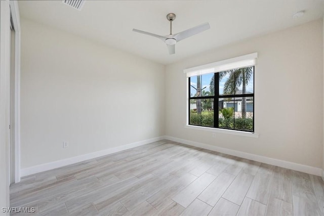 spare room featuring a ceiling fan, visible vents, light wood-style flooring, and baseboards