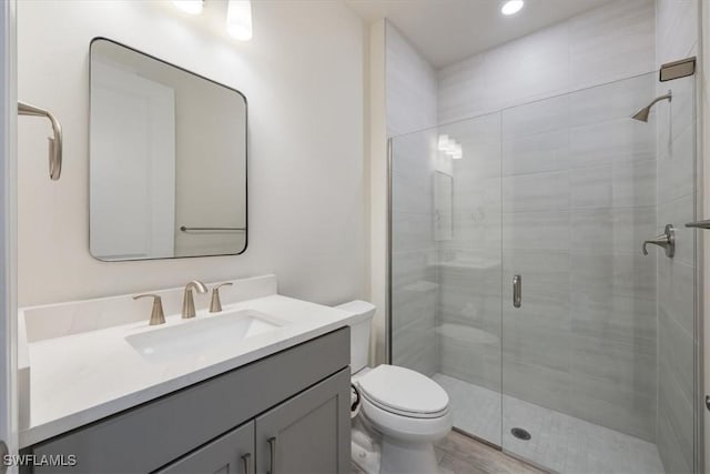 bathroom with a shower stall, vanity, and toilet