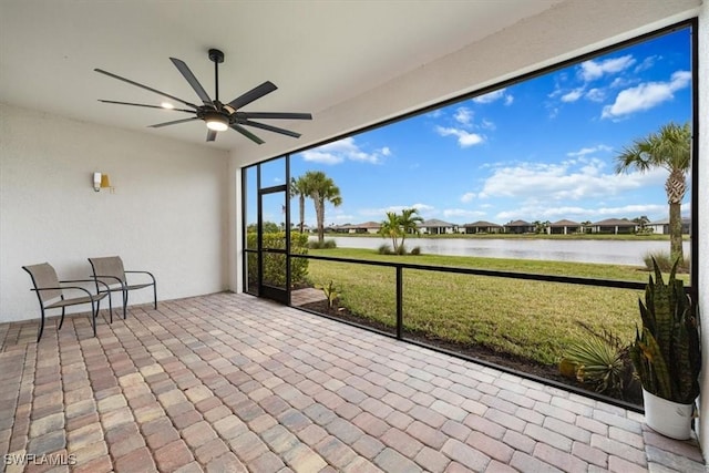 unfurnished sunroom with a ceiling fan and a water view