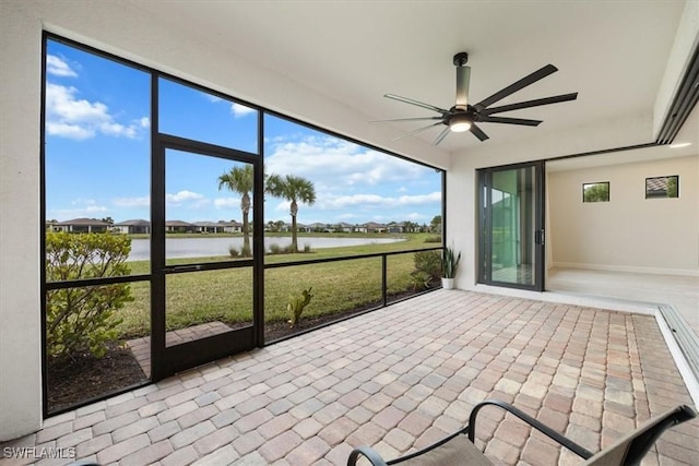 unfurnished sunroom with a water view and ceiling fan