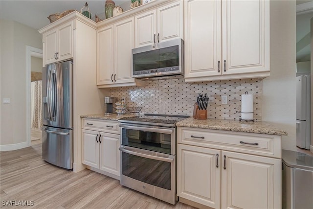 kitchen with stainless steel appliances, backsplash, light wood-type flooring, light stone countertops, and baseboards