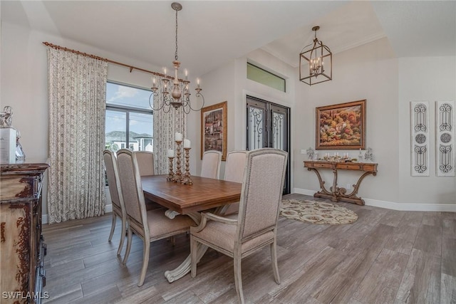 dining space with baseboards, wood finished floors, and a notable chandelier