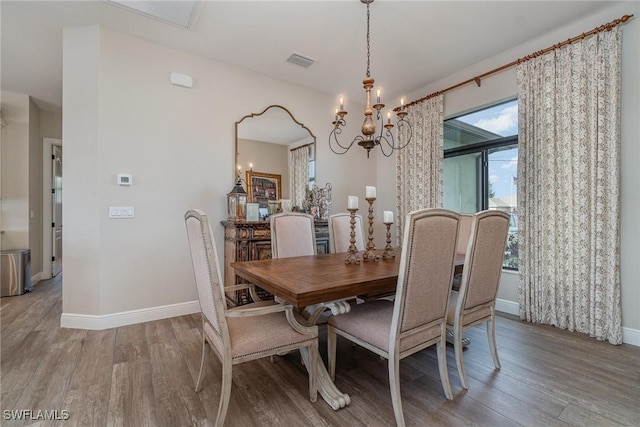 dining room featuring an inviting chandelier, wood finished floors, visible vents, and baseboards