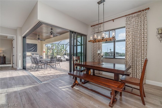 dining room featuring wood finished floors, baseboards, and ceiling fan with notable chandelier
